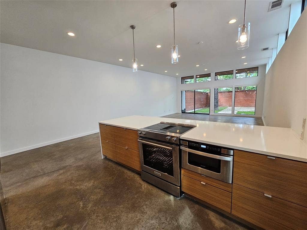 4215 Roseland Avenue, Dallas, TX 75204 Modern kitchen island featuring wood-finish cabinetry, quartz countertops, a stainless steel range, and a built-in microwave