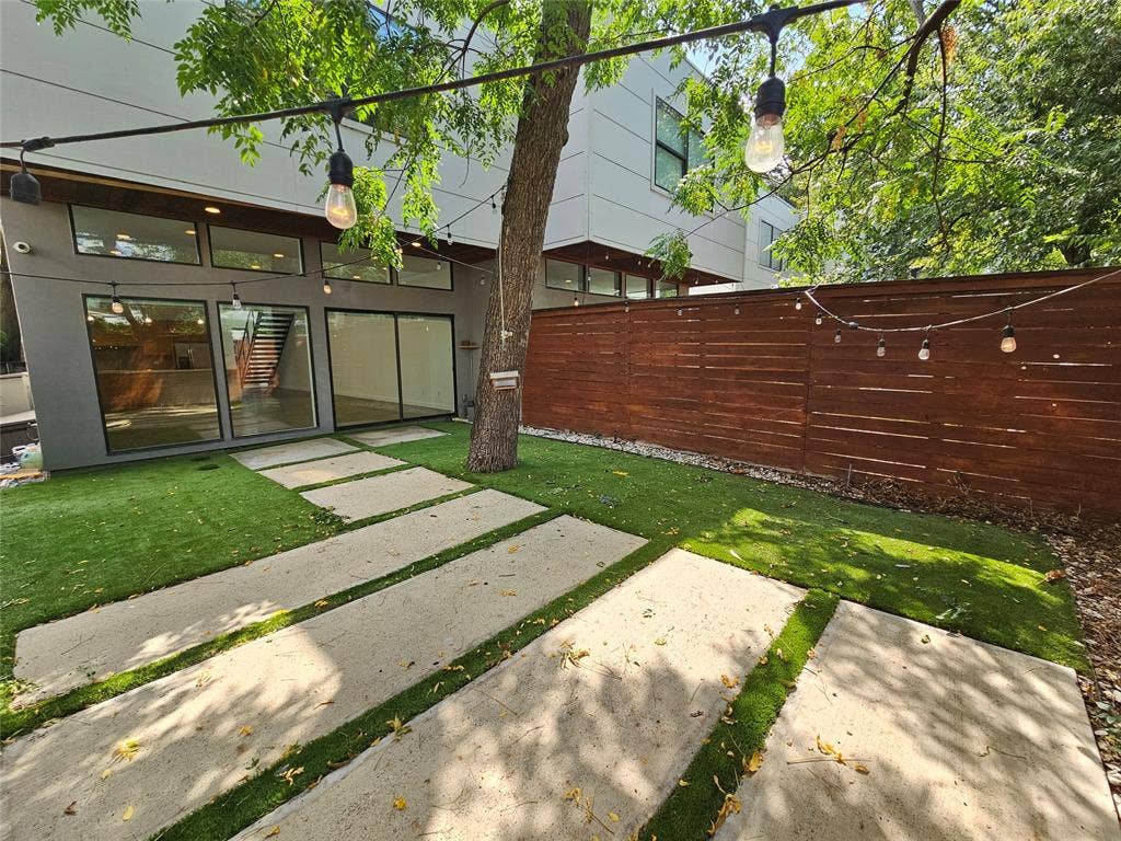4215 Roseland Avenue, Dallas, TX 75204 Private rear courtyard featuring large-format concrete pavers, synthetic turf, horizontal wood privacy fencing, and exterior wall-mounted transom windows
