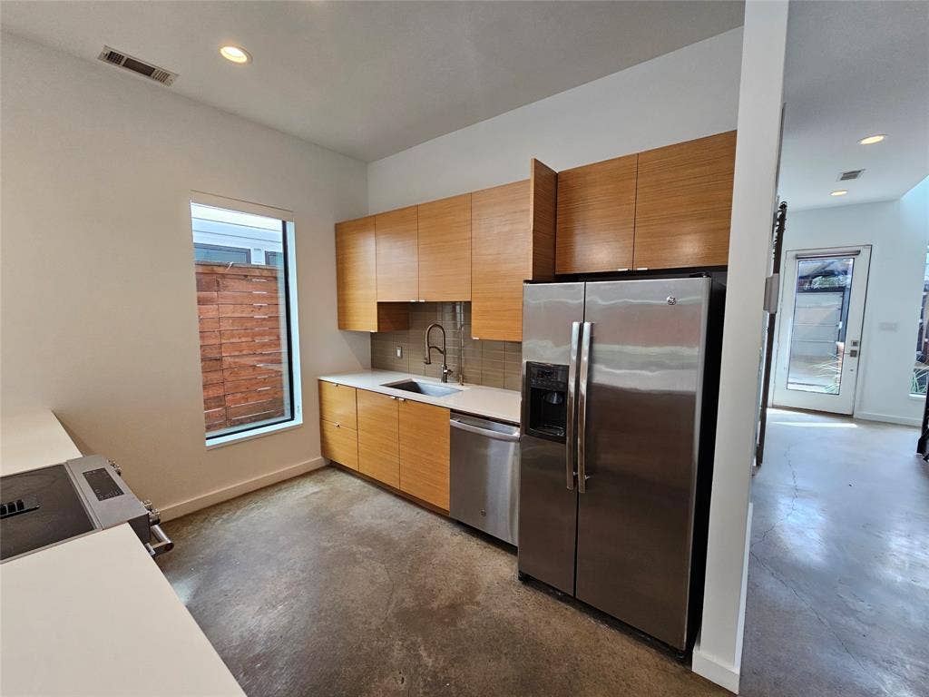 4215 Roseland Avenue, Dallas, TX 75204 Kitchen featuring flat-panel wood cabinetry, white countertops, stainless steel appliances, and concrete flooring