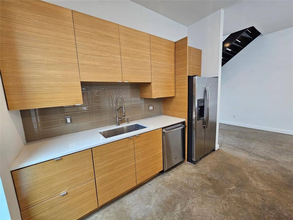 4215 Roseland Avenue, Dallas, TX 75204 Flat-panel wood-finish cabinetry, white solid-surface countertops, stainless steel appliance suite, tiled backsplash, and polished concrete flooring