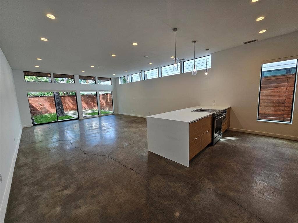 4215 Roseland Avenue, Dallas, TX 75204 Open-concept living space featuring polished concrete flooring, a kitchen island with stone countertops, wood-finish cabinetry, recessed lighting, and expansive floor-to-ceiling windows