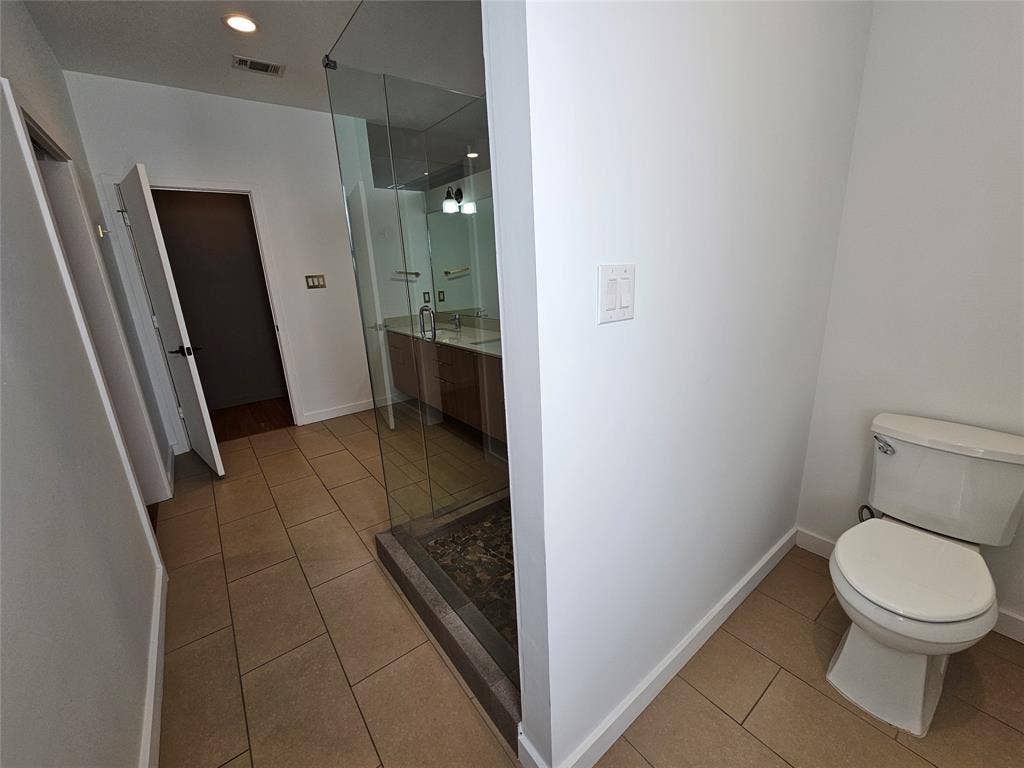 4215 Roseland Avenue, Dallas, TX 75204 Bathroom featuring large-format tile flooring, a glass-enclosed shower with stone floor inlay, a wood-finish vanity, and recessed lighting