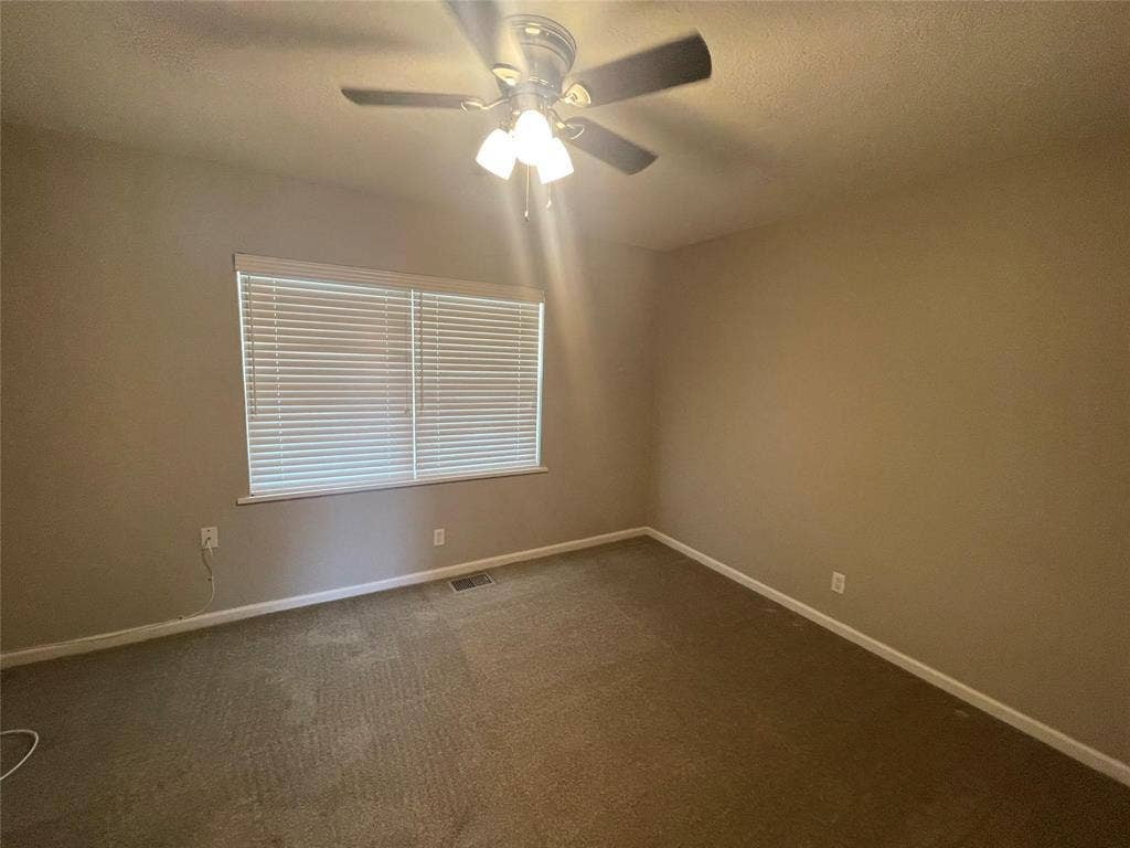 Carpeted spare room featuring ceiling fan