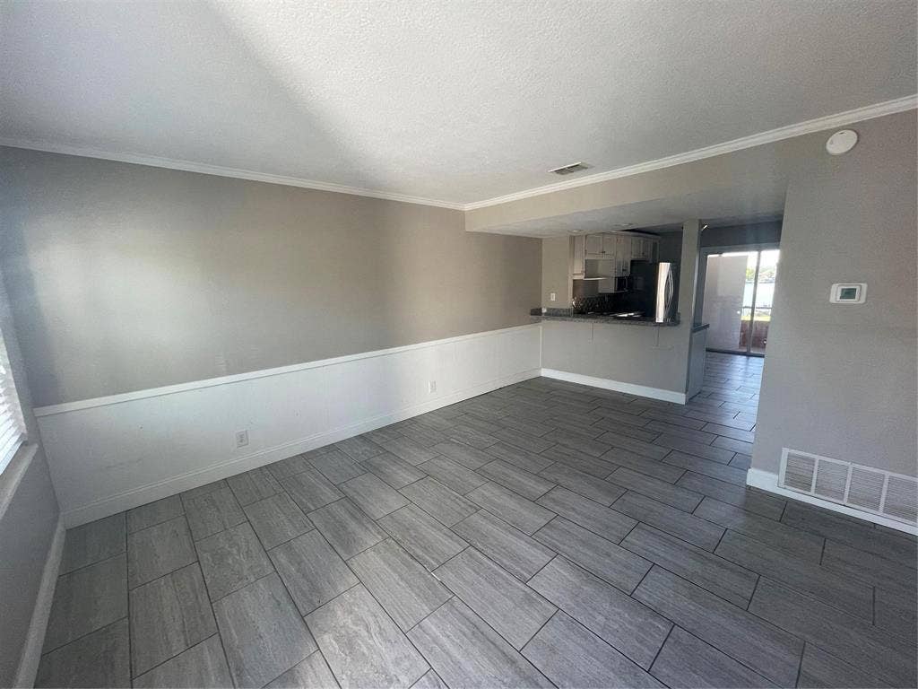Unfurnished living room featuring crown molding and a textured ceiling