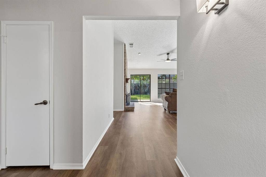 Entryway featuring wood-finish flooring, a wall-mounted light fixture, a ceiling fan, and a floor-to-ceiling brick fireplace surround