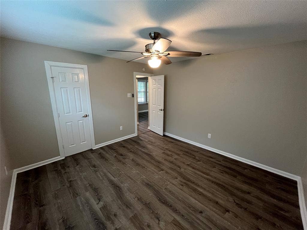 Wood-finish flooring, neutral wall paint, and a ceiling fan with integrated lighting