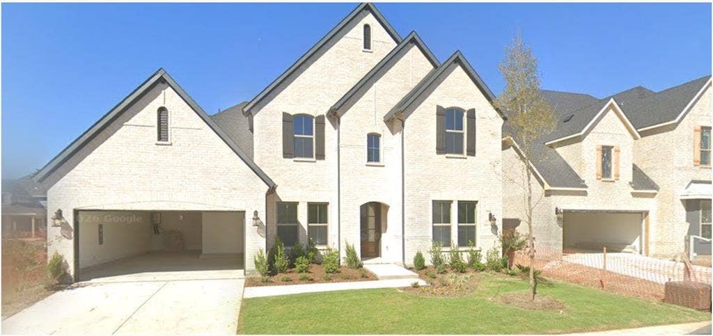 Two-story exterior featuring light brick masonry, multi-gabled roofline, dark-toned window shutters, and attached multi-car garage