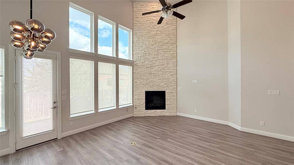 315 Chandan Way, Irving, TX 75063 Floor-to-ceiling stone fireplace, soaring vaulted ceilings, wall of multi-pane windows, wood-finish flooring, and multi-globe chandelier