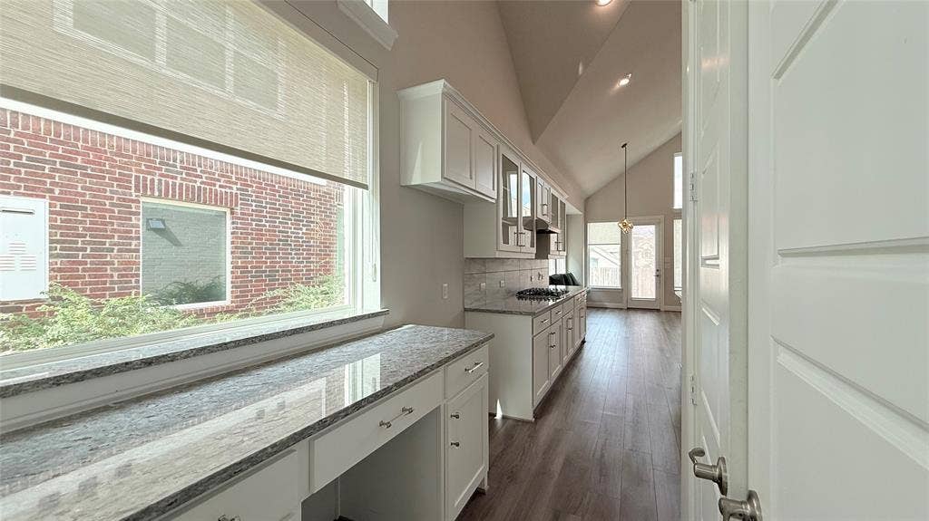 315 Chandan Way, Irving, TX 75063 Vaulted ceiling with recessed lighting, stone-surface countertops, custom white cabinetry, and wood-finish flooring