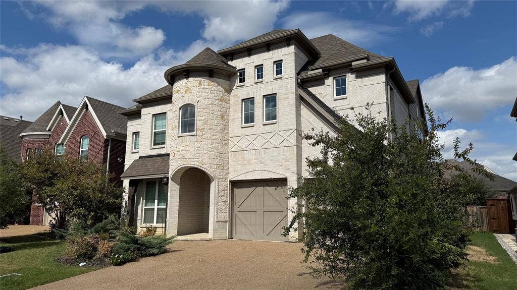 315 Chandan Way, Irving, TX 75063 Multi-story exterior featuring light-toned masonry, prominent turret architectural element, multi-gabled roofline, and garage with carriage-style doors