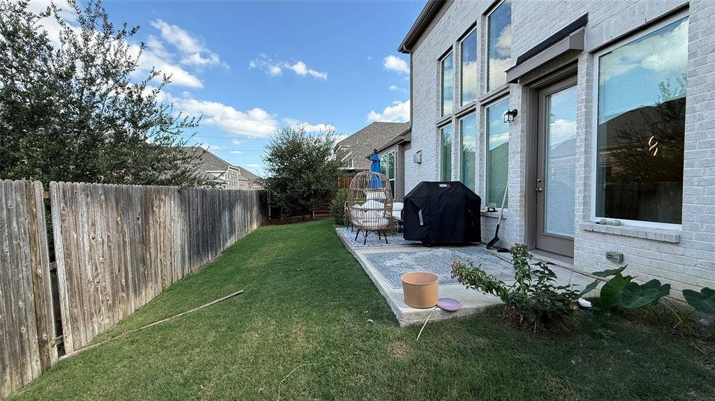 315 Chandan Way, Irving, TX 75063 White brick exterior featuring floor-to-ceiling windows, a rear concrete patio, and perimeter wood fencing