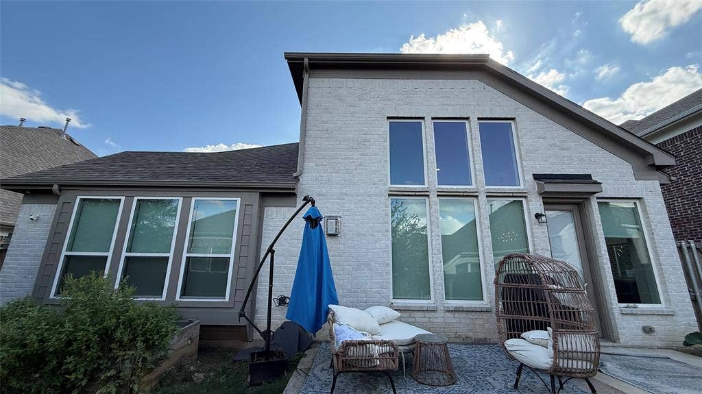 315 Chandan Way, Irving, TX 75063 Light-colored brick exterior featuring high-pitched rooflines, expansive vertical windows, and a paved outdoor patio area