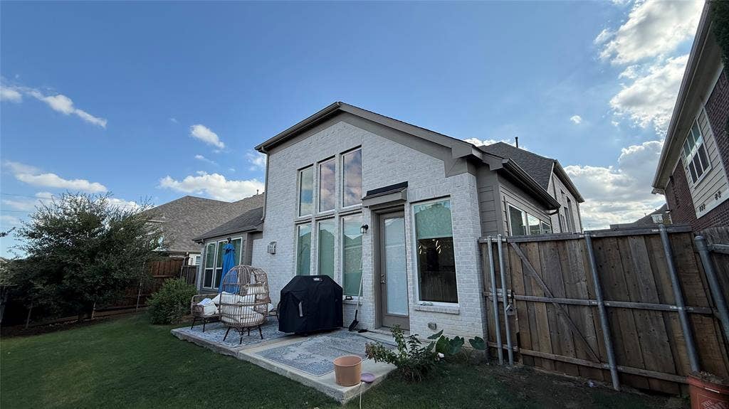 315 Chandan Way, Irving, TX 75063 Exterior featuring painted brick siding, vertical windows, a concrete patio, and a wood privacy fence
