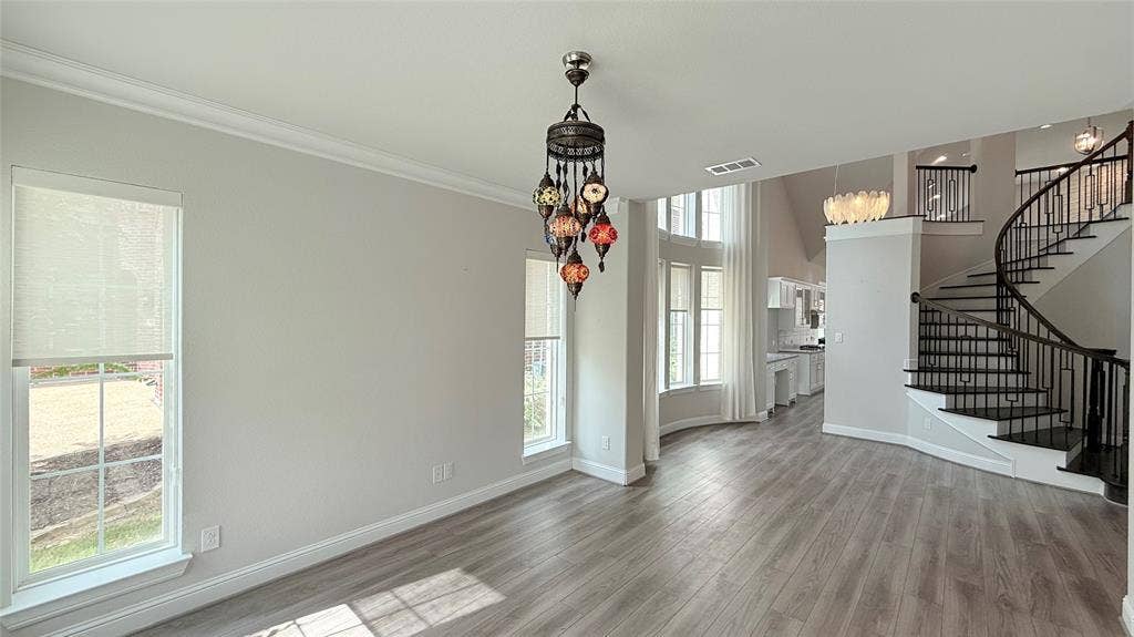 315 Chandan Way, Irving, TX 75063 Interior featuring wood-finish flooring, multi-pane windows, a decorative multi-light pendant fixture, and a curved staircase with metal railings