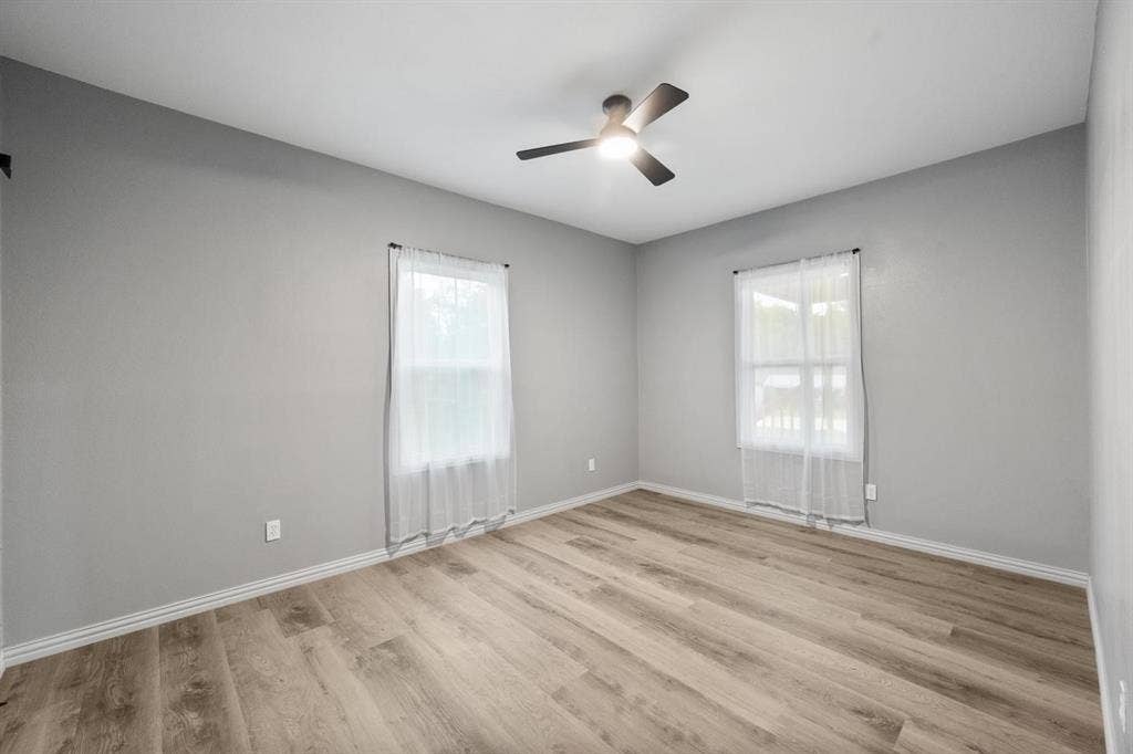 Unfurnished bedroom featuring wood-finish flooring, neutral walls, and a modern ceiling fan with integrated lighting