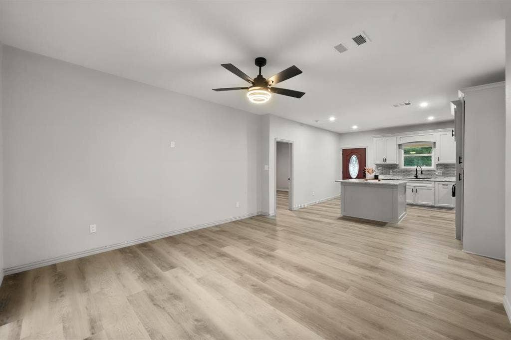 Open-concept interior featuring wood-finish flooring, a central kitchen island, recessed lighting, and a modern ceiling fan