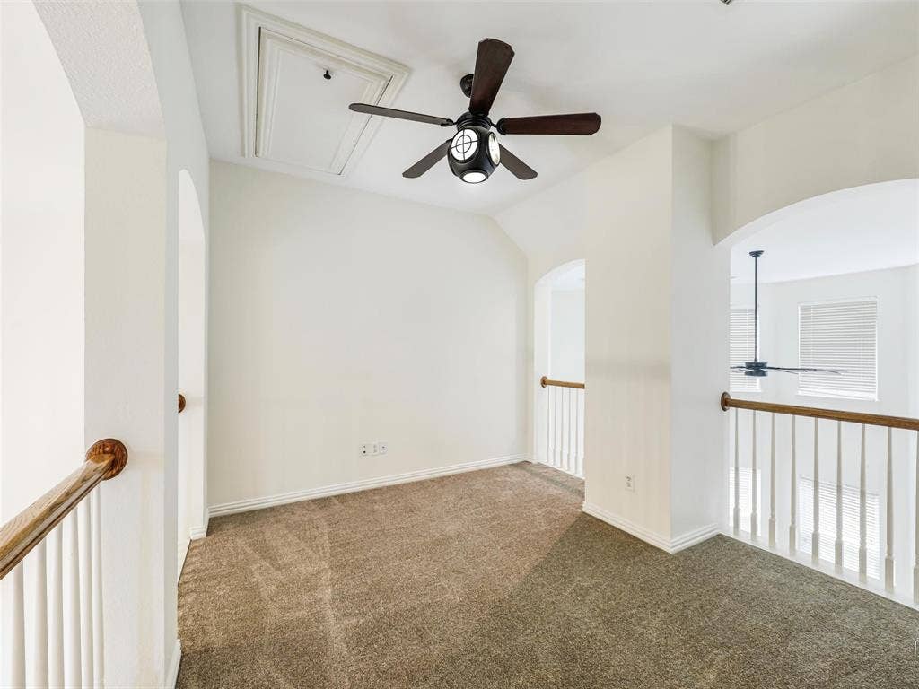 3504 Anita Drive, McKinney, TX 75070 Neutral carpeted floor, ceiling fan with integrated lighting, arched architectural openings, and white balustrade railing
