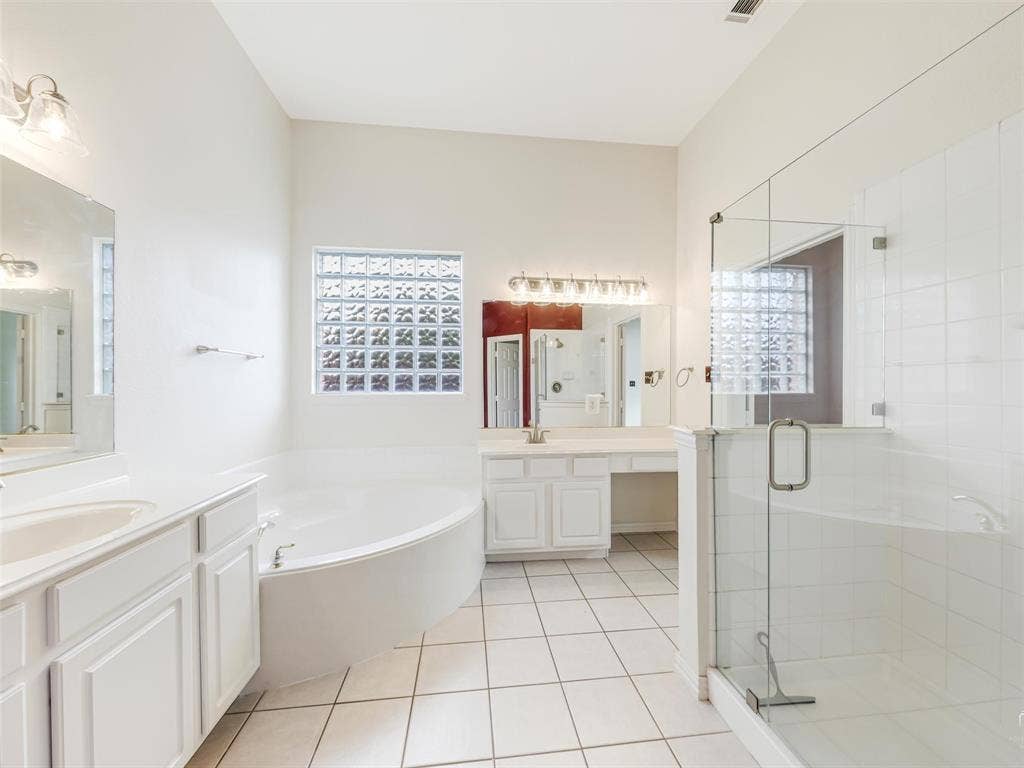 3504 Anita Drive, McKinney, TX 75070 Bathroom featuring a glass-enclosed walk-in shower, a soaking tub, dual-sink vanity with white cabinetry, square glass block window, and ceramic tile flooring
