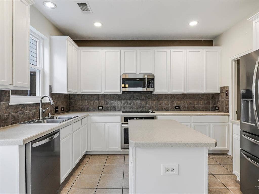3504 Anita Drive, McKinney, TX 75070 Kitchen featuring white shaker-style cabinetry, a central island with countertop seating, stainless steel appliances, tile backsplash, and ceramic tile flooring