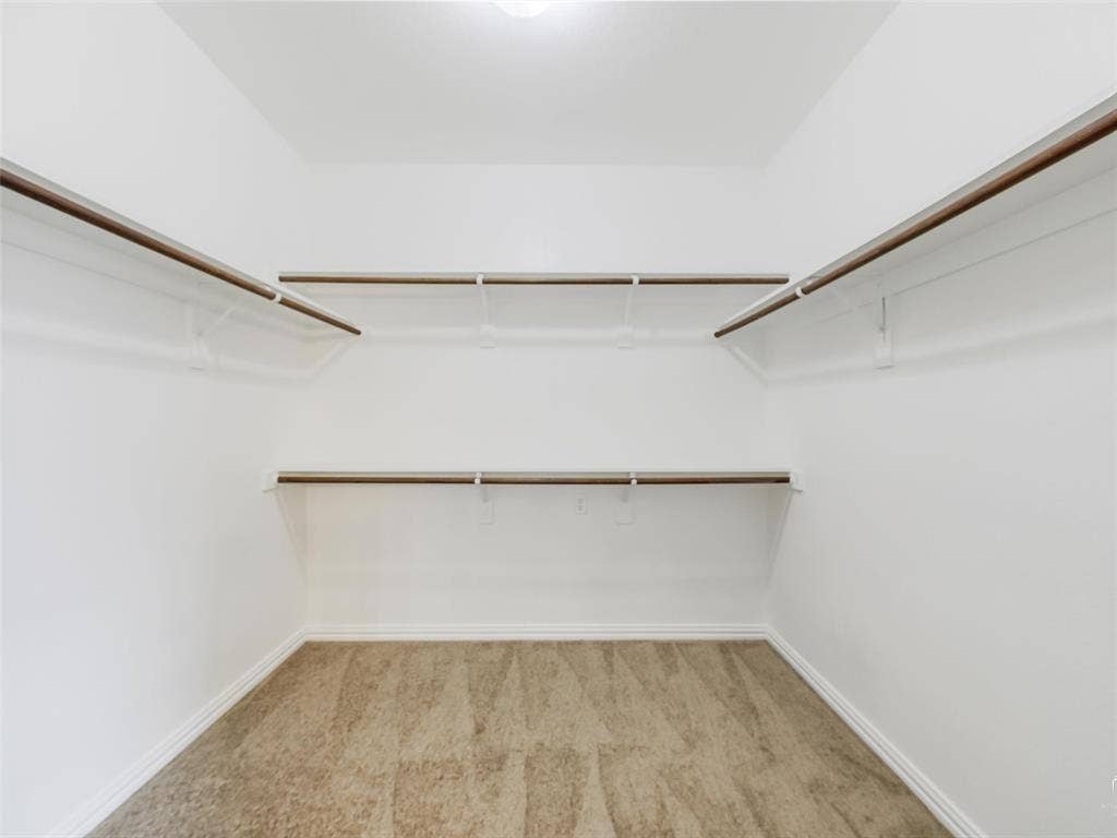 3504 Anita Drive, McKinney, TX 75070 Walk-in closet featuring tiered shelving with integrated hanging rods and carpeted flooring