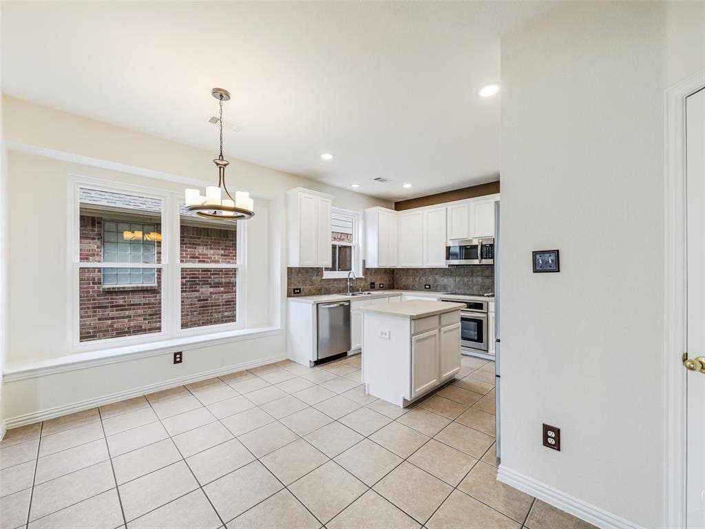 3504 Anita Drive, McKinney, TX 75070 Kitchen featuring white shaker-style cabinetry, central island, tile flooring, stainless steel appliances, and a built-in window seat