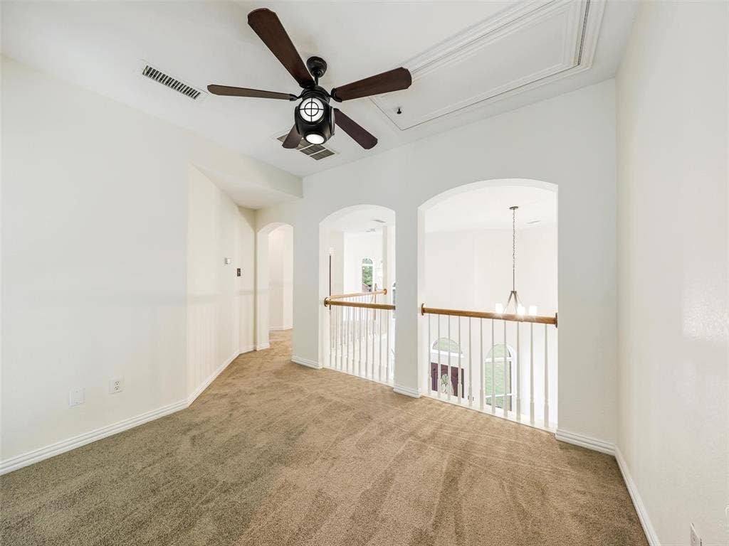 3504 Anita Drive, McKinney, TX 75070 Interior space featuring arched architectural cutouts, a ceiling fan with integrated lighting, and a balustrade railing with a wood-finish handrail