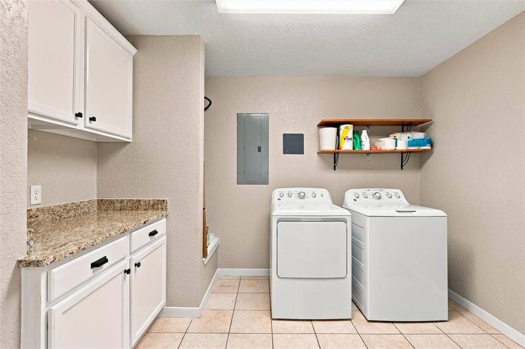 813 Chambers Creek Circle, Hewitt, TX 76643 Laundry space featuring white cabinetry, stone-finish countertops, tile flooring, and wall-mounted shelving