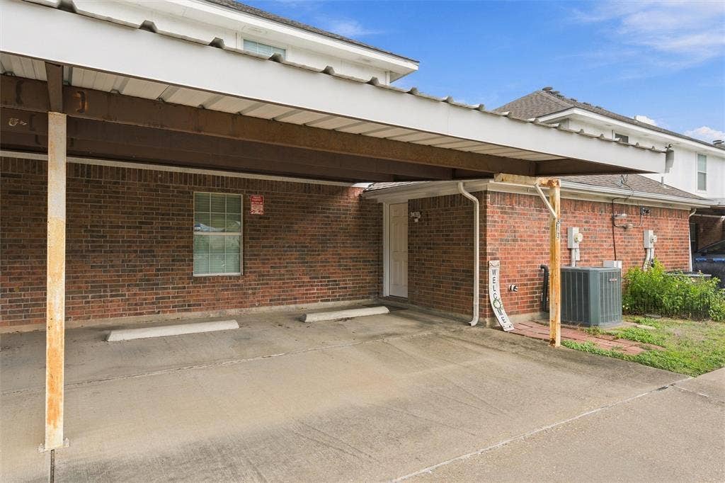 813 Chambers Creek Circle, Hewitt, TX 76643 Covered carport featuring a concrete parking pad, brick exterior, and metal roof structure
