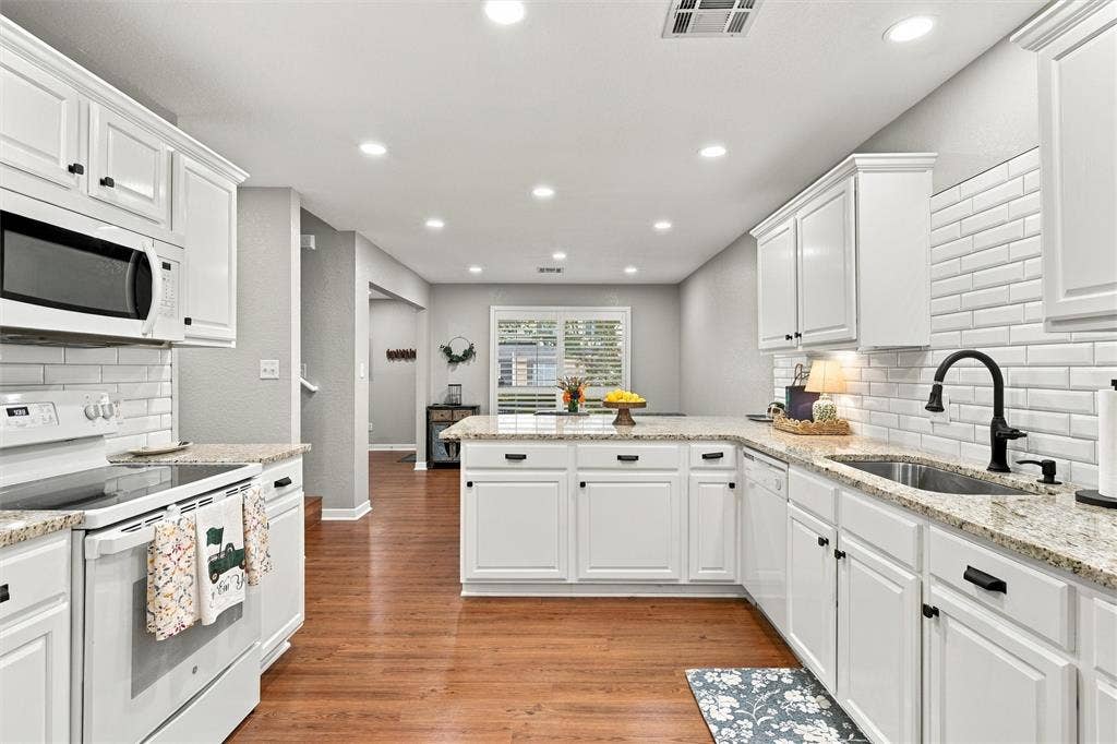 813 Chambers Creek Circle, Hewitt, TX 76643 Kitchen featuring white cabinetry, stone countertops, white subway tile backsplash, matte black hardware, and wood-finish flooring
