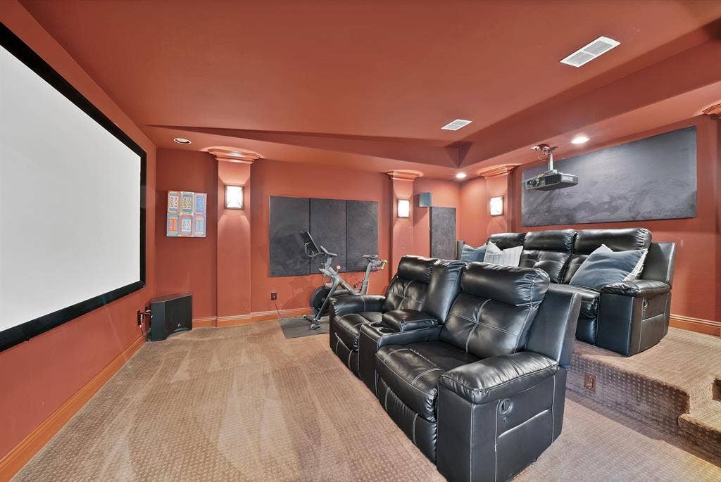 2141 Waterrock Drive, Allen, TX 75013 Media space featuring a large-format wall-mounted projection screen, tiered flooring, integrated wall sconce lighting, and decorative column accents