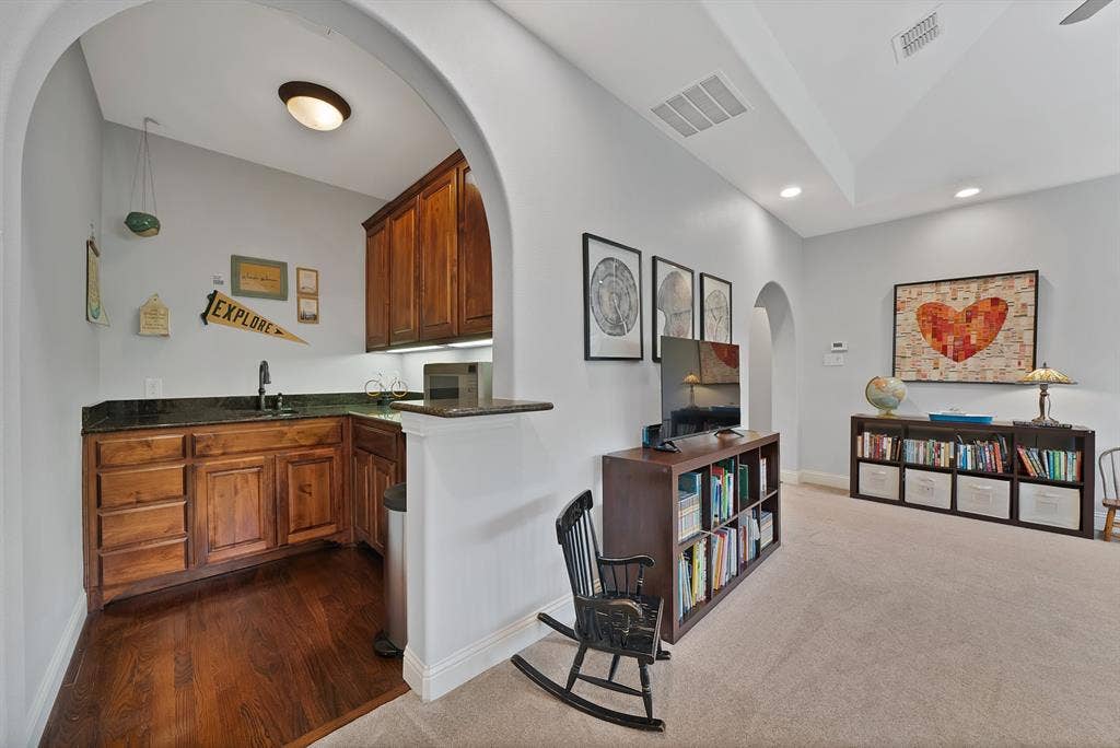 2141 Waterrock Drive, Allen, TX 75013 Arched entryway featuring stained wood cabinetry, stone countertops, dark-finish faucet, and recessed lighting