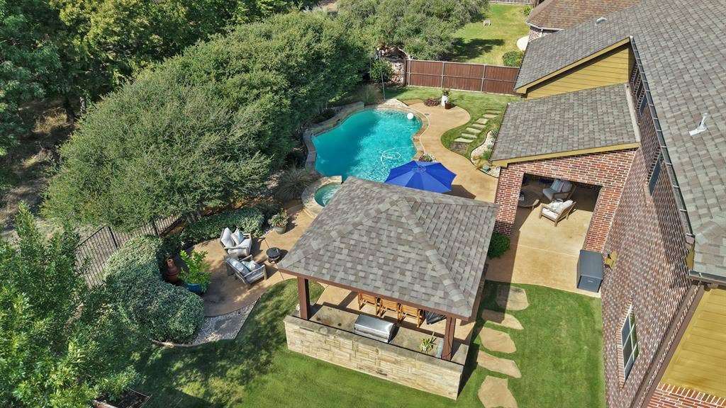 2141 Waterrock Drive, Allen, TX 75013 Backyard featuring an in-ground swimming pool, integrated spa, covered patio, stone-veneer outdoor kitchen, and a detached gazebo with shingled roofing