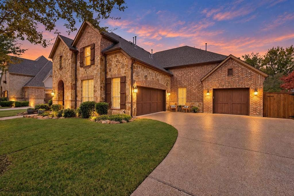 2141 Waterrock Drive, Allen, TX 75013 Stone and brick exterior facade featuring a multi-car garage, steep roof lines, wood-finish shutters, and professional landscape edging