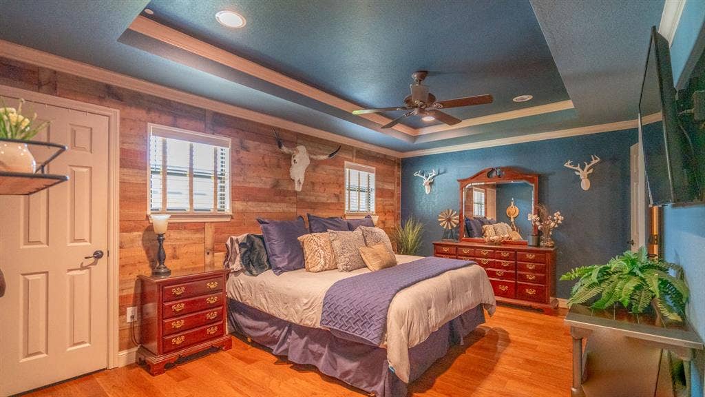 4015 Sioux Court, Granbury, TX 76048 Primary bedroom with wood flooring and a wood accent wall, trayed ceiling and recessed lighting