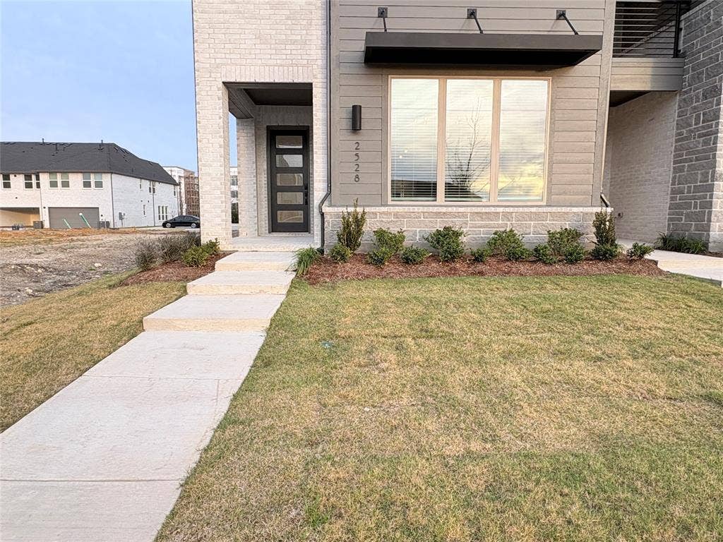 2528 Brunswick Way, Allen, TX 75013 Modern exterior featuring a combination of brick and horizontal siding, a multi-pane glass entry door, stone-veneer accents, and a contemporary metal window awning