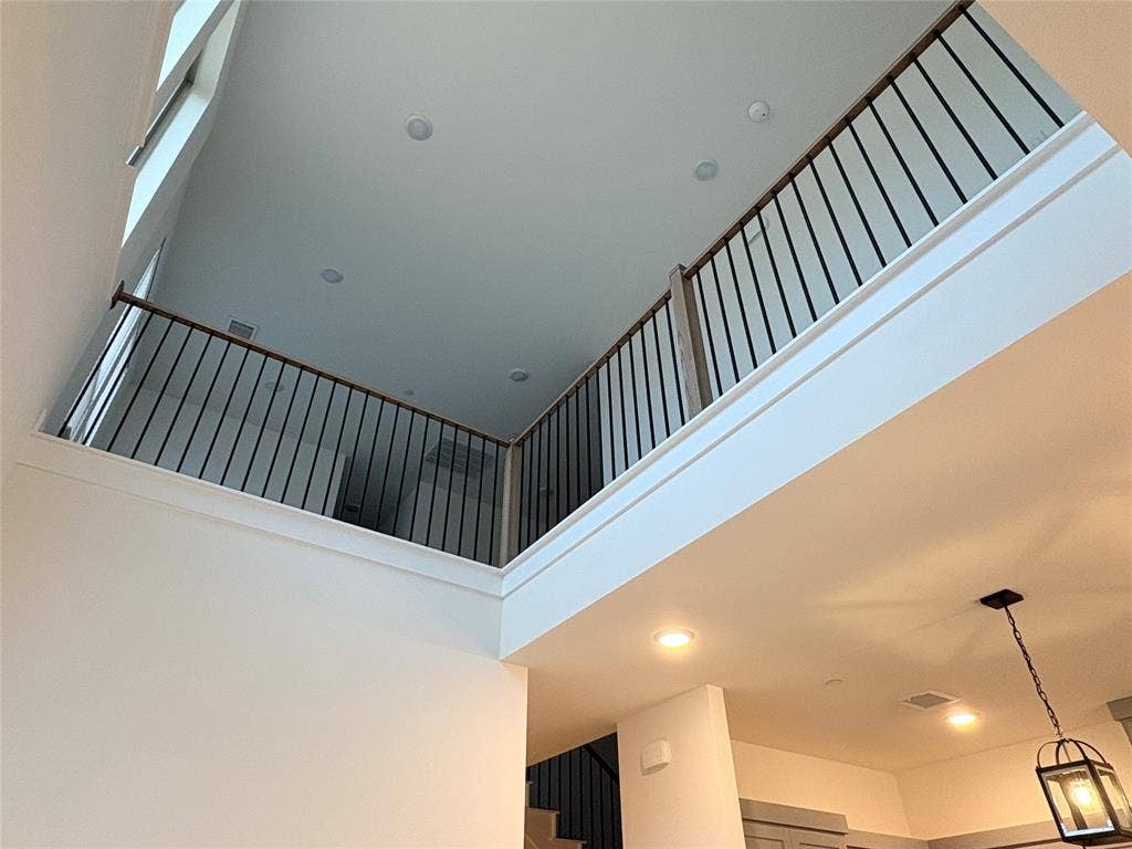 2528 Brunswick Way, Allen, TX 75013 High-ceiling interior featuring a mezzanine overlook with black metal balusters, wooden handrails, recessed lighting, and a pendant fixture