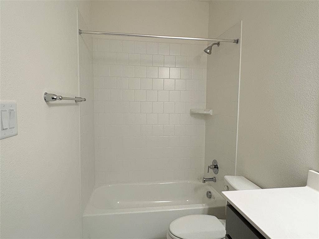 2528 Brunswick Way, Allen, TX 75013 Bathtub and shower combination with white tile surround, chrome fixtures, built-in soap dish, and vanity with countertop