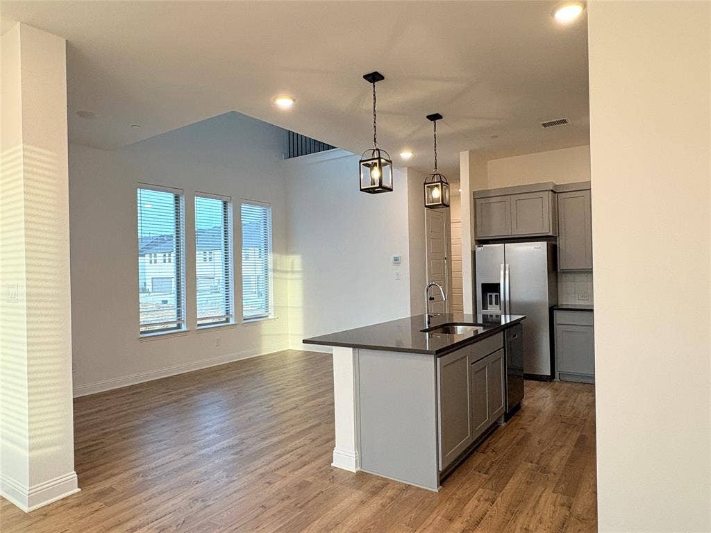2528 Brunswick Way, Allen, TX 75013 Kitchen featuring wood-finish flooring, a central island with a stone-surface countertop, recessed lighting, and dual pendant light fixtures