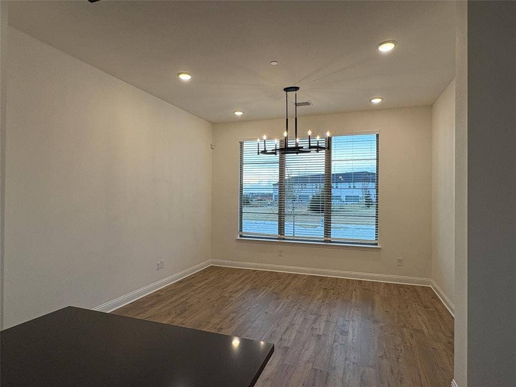 2528 Brunswick Way, Allen, TX 75013 Room featuring wood-finish flooring, recessed lighting, a modern multi-arm chandelier, and a large multi-pane window with horizontal blinds