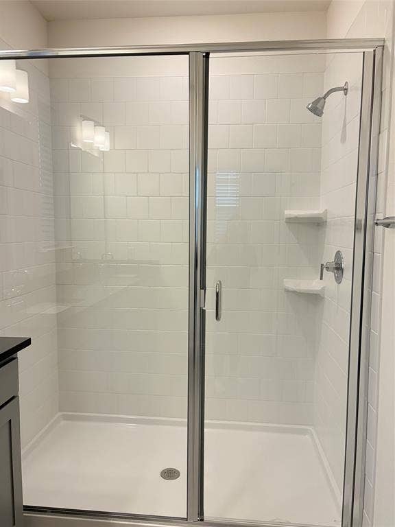 2528 Brunswick Way, Allen, TX 75013 Walk-in shower featuring white subway-style wall tile, built-in shelving, chrome fixtures, and a glass enclosure with a metal frame