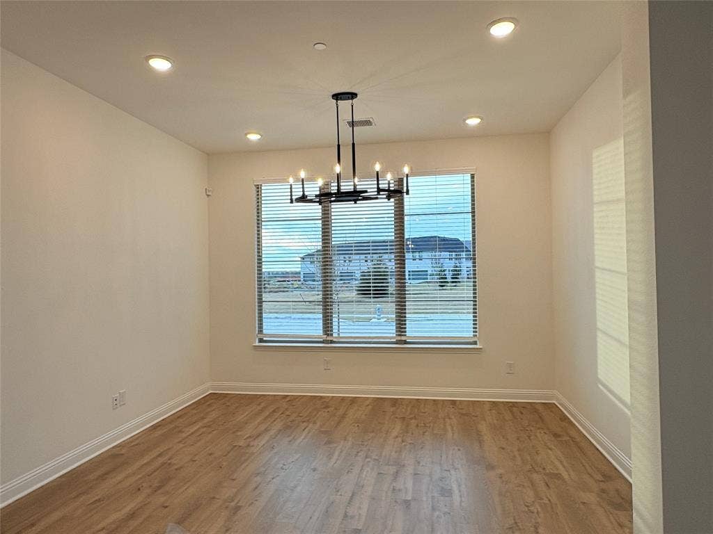 2528 Brunswick Way, Allen, TX 75013 Room featuring wood-finish flooring, a tiered matte black chandelier, recessed lighting, and large windows with horizontal blinds