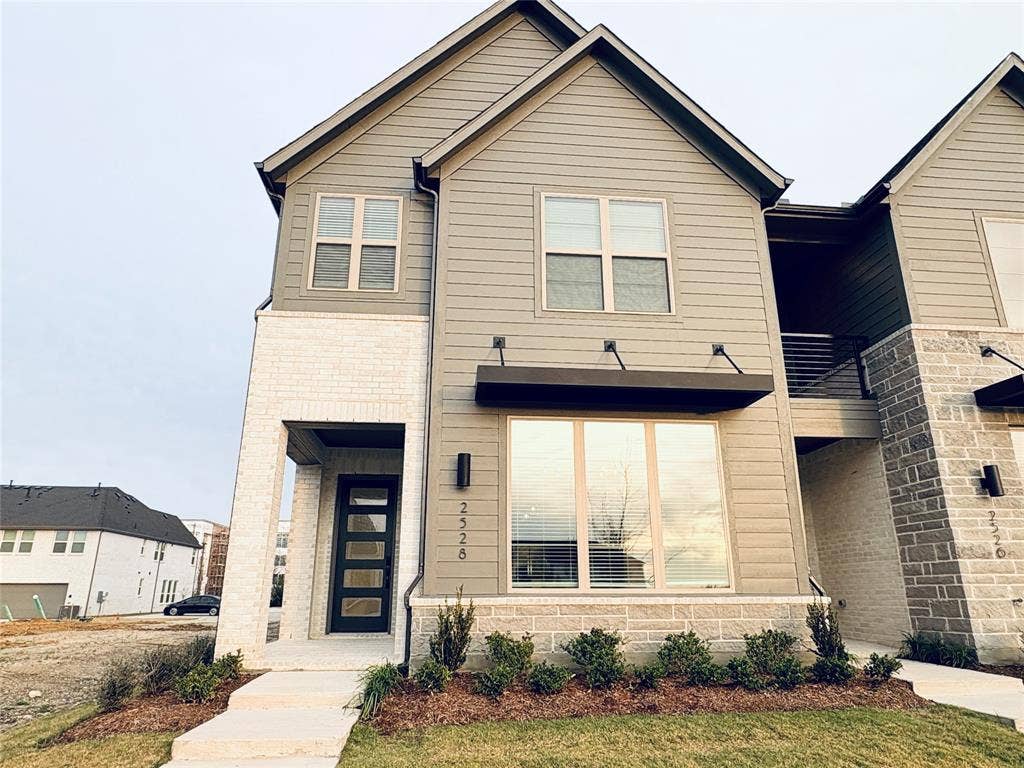 2528 Brunswick Way, Allen, TX 75013 Exterior featuring horizontal lap siding, white brick masonry, a modern multi-panel glass front door, metal awning, and wall-mounted exterior lighting