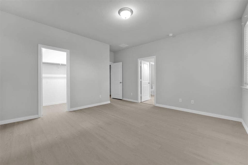 Spacious room with wood-finish flooring and neutral wall tones