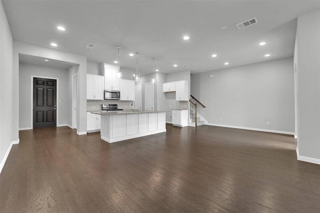 Open-concept living space featuring wood-finish flooring, recessed lighting, and a kitchen island with pendant lighting