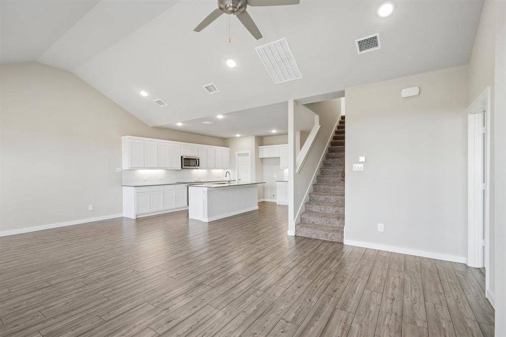 135 Lost Maples Way, Waxahachie, TX 75165 Vaulted ceilings featuring a ceiling fan, white cabinetry, a center island with a stone countertop, recessed lighting, and wood-finish flooring