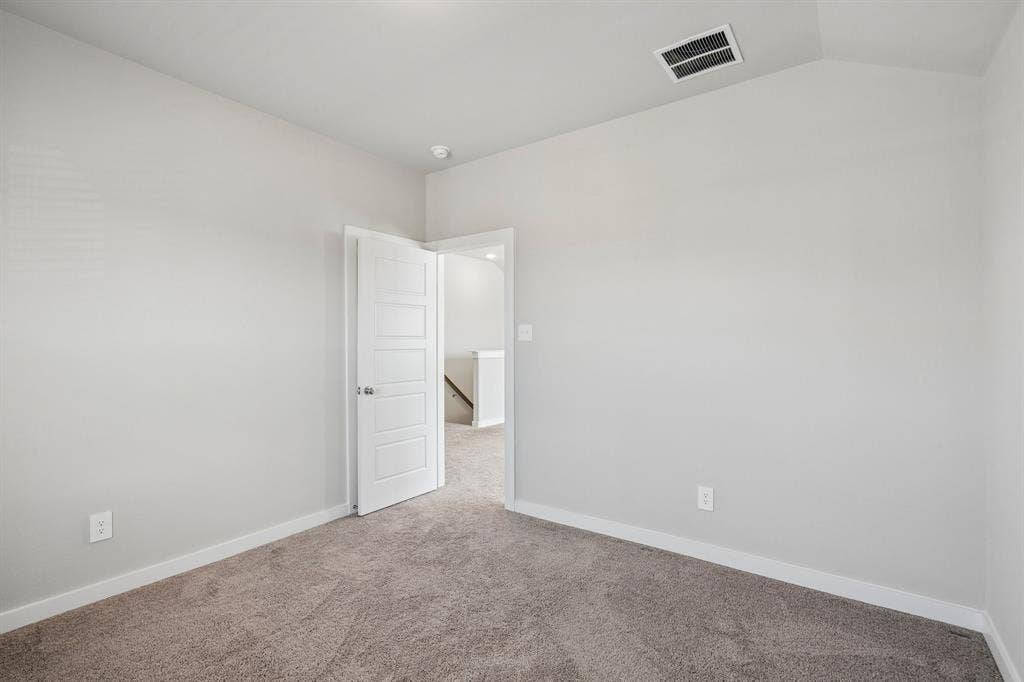 135 Lost Maples Way, Waxahachie, TX 75165 Neutral-toned interior space featuring neutral carpeting, a vaulted ceiling, and a solid-core four-panel interior door