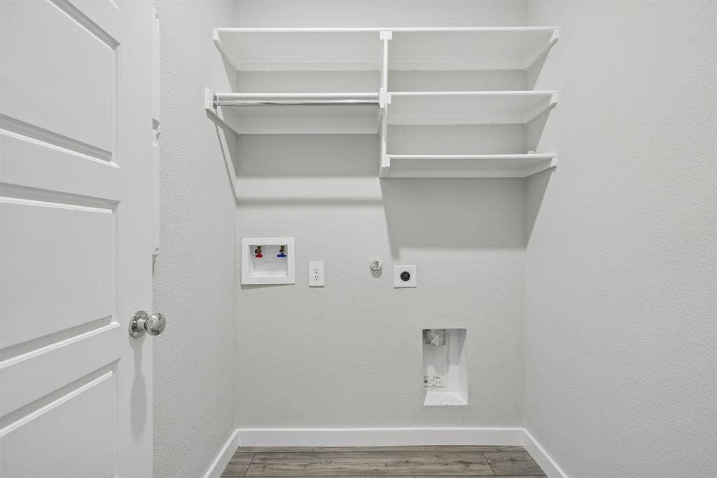 135 Lost Maples Way, Waxahachie, TX 75165 Utility space featuring wood-finish flooring, white shelving with integrated clothing rods, and dedicated water and electrical hookups