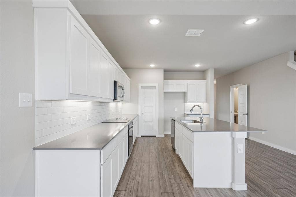 135 Lost Maples Way, Waxahachie, TX 75165 Kitchen featuring white cabinetry, quartz countertops, subway tile backsplash, stainless steel appliances, and wood-finish flooring