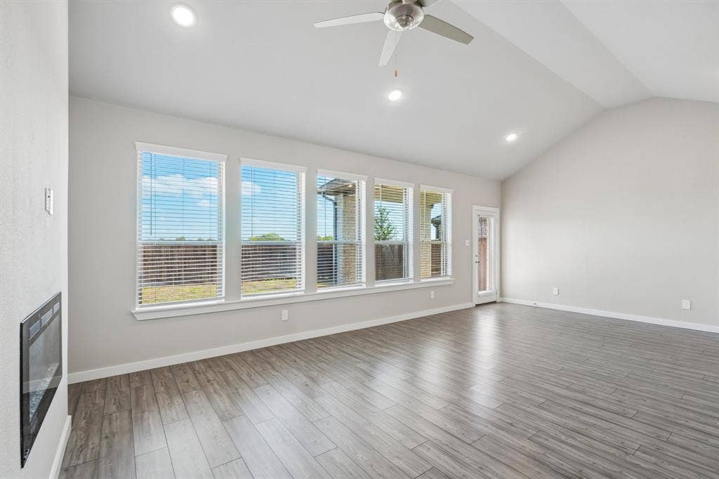135 Lost Maples Way, Waxahachie, TX 75165 Vaulted ceilings, wood-finish flooring, recessed lighting, wall-mounted electric fireplace, and expansive windows