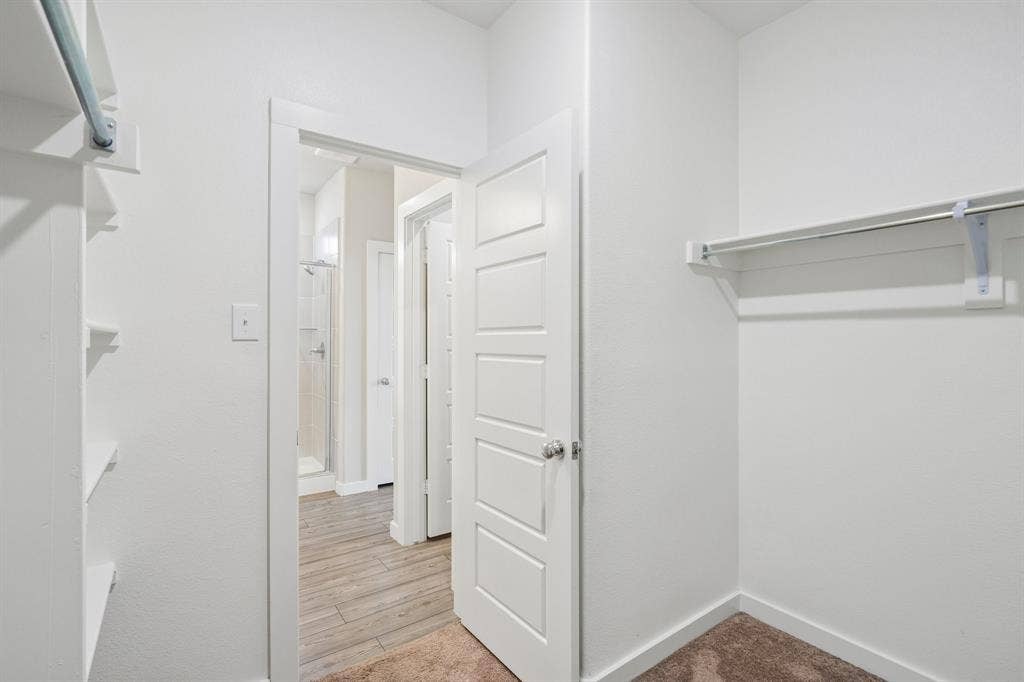 135 Lost Maples Way, Waxahachie, TX 75165 Walk-in closet featuring white built-in shelving, a hanging rod, a five-panel interior door, and neutral carpeting